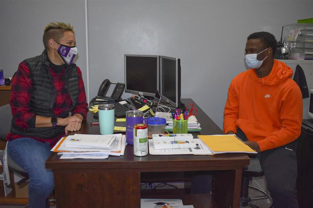 Teacher and students sitting at a desk talking